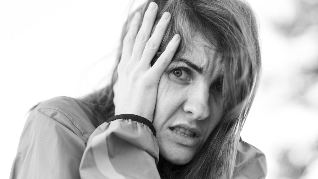 a black and white photo of a woman covering her face, transforming negative thoughts