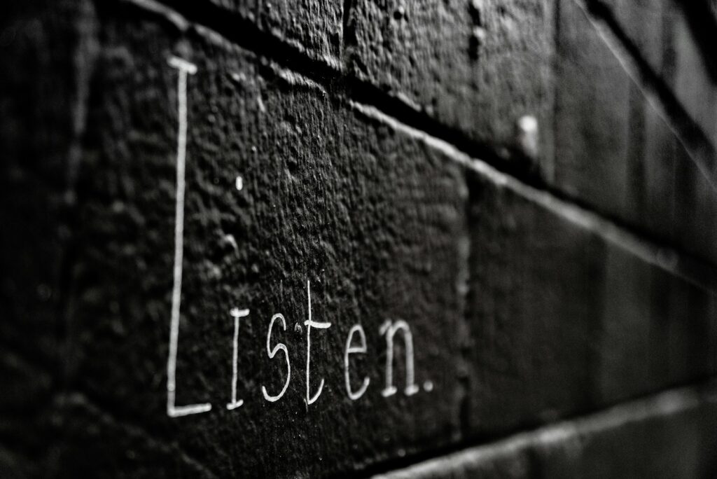 a black and white photo of the word listen written on a brick wall