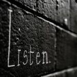 a black and white photo of the word listen written on a brick wall